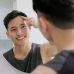 A man looking at his reflection in the mirror.