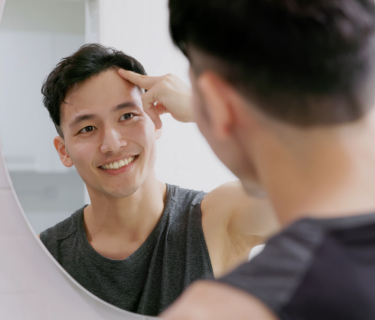 A man looking at his reflection in the mirror.