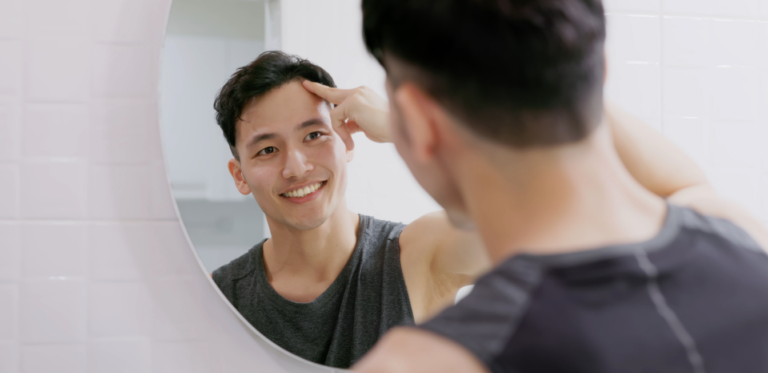 A man looking at his reflection in the mirror.